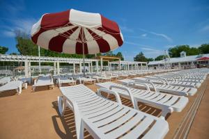 - une rangée de chaises longues blanches avec un parasol dans l'établissement Bethpage Two-Bedroom Cottage 4, à Urbanna