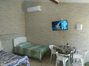 a room with a table and a tv on the wall at Itaipuaçu Residencia Cajueiros I in Itaipuaçu