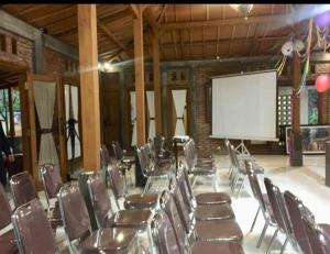 a conference room with chairs and a white screen at Omah Joglo Semarang in Semarang