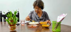 Hostel Gandhi في تشيناي: امرأة تجلس على طاولة تأكل الطعام