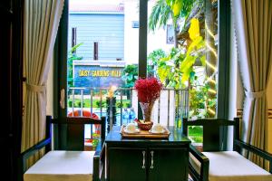 a balcony with a table and two chairs and a window at Daisy Garden Villa Hoi An in Hoi An