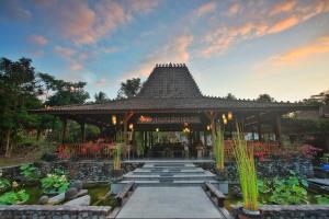 un pavillon avec un étang dans un jardin dans l'établissement Amata Borobudur Resort, à Borobudur