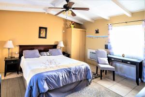 a bedroom with a bed with a ceiling fan and a desk at Harmony Motel in Twentynine Palms