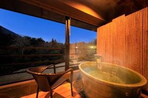 a bathroom with a tub and a chair and a window at Hakone Fuga (Adult Only) in Hakone