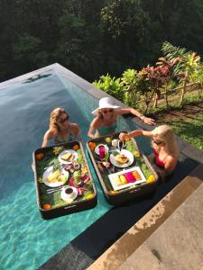 een groep mensen in een zwembad met voedsel in het water bij Alami Villa in Ubud