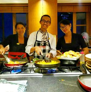 un grupo de tres personas preparando comida en una cocina en The Longhouse, Jimbaran - Bali, en Jimbaran