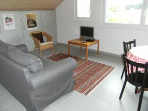 a living room with a couch and a table with a television at BnB Niederer in La Côte-aux-Fées