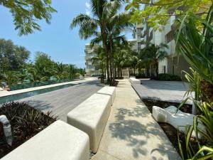 a walkway with benches and palm trees next to a building at By The Sea @ Luxury Suites, Batu Ferringhi in Batu Ferringhi