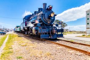 a blue train on the tracks next to a street at Dolphin 1 in Rockaway Beach