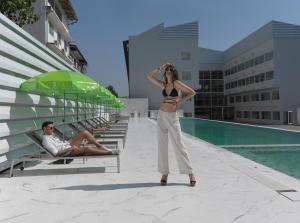 una mujer está parada frente a una piscina en S Ram Leisure Hotel SHA PLUS, en Bangkok