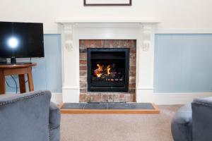 a living room with a fireplace with two chairs and a tv at Akaroa Streamside Cottage in Akaroa