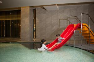 dwójka dzieci bawiących się na zjeżdżalni w basenie w obiekcie Hotel Tops 10 w mieście Gangneung