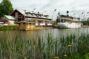 zwei Boote sind neben einem Gebäude auf einem Fluss angedockt. in der Unterkunft Kapten Billes Restaurang och Logi in Norsholm