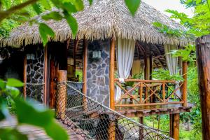 Cette maison dispose d'un toit de chaume et d'un balcon. dans l'établissement CASA CONTIKI, à Cabo Matapalo