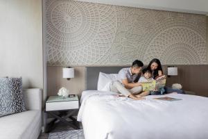 una familia sentada en una cama leyendo un libro en Clark Marriott Hotel, en Clark