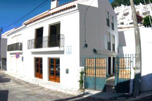 a white building with a gate on a street at Lá em Cima in Sesimbra
