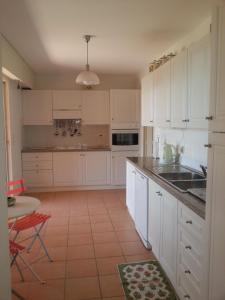 uma cozinha com armários brancos, um lavatório e uma mesa em Rochemarine em Théoule-sur-Mer