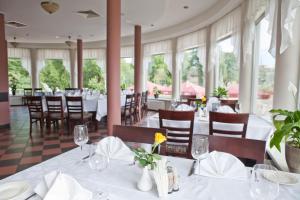 a dining room with tables and chairs and windows at Kolonna Hotel Rēzekne in Rēzekne