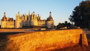 un grande edificio sullo sfondo con un muro di Chambre d'hôte Montlivault / Chambord a Montlivault