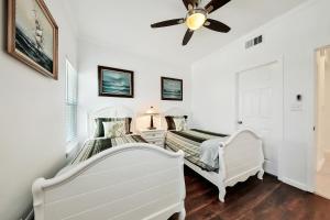 two beds in a room with a ceiling fan at Oceanview by the Galvez in Galveston