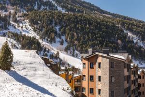 ein Gebäude im Schnee mit einem Berg im Hintergrund in der Unterkunft Pierre & Vacances Andorra El Tarter in El Tarter