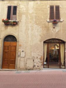 un edificio con dos puertas y una ventana con flores en Il Nido Di Anna, en San Gimignano
