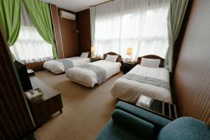 a hotel room with two beds and a couch at Hotel Ra Kuun in Hakone