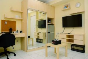 Habitación con TV, escritorio y silla. en Chic and Cozy Studio Apartment at Menteng Square By Travelio en Yakarta