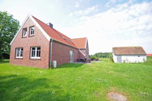 uma casa de tijolos com um quintal relvado ao lado de um edifício em Ferienhaus Adamla, 65319 em Moormerland