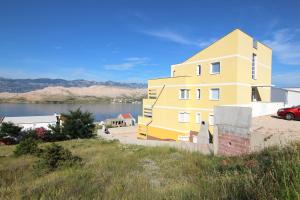 a yellow building on the side of a body of water at Amazing sea view apartments Ljubic in Pag