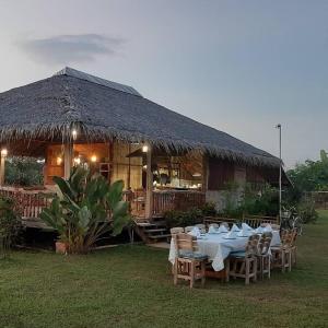 a table and chairs in front of a hut at Kham Ecolodge in Chiang Saen
