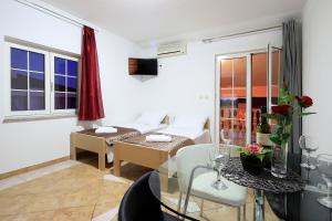 a living room with a bed and a glass table at Pink House Apartments in Novalja