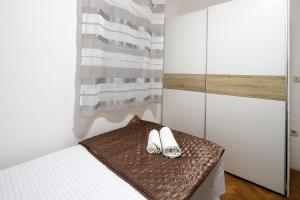 a bedroom with two pairs of shoes on a bed at Pink House Apartments in Novalja