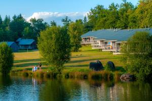 une maison à côté d'un lac avec des gens qui s'y promenent dans l'établissement Goélia Le Domaine des Nouailles, à Nontron