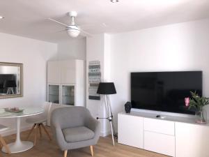 ein Wohnzimmer mit einem TV, einem Stuhl und einem Tisch in der Unterkunft Primera Linea de Playa in Moraira