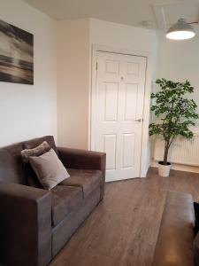 a living room with a brown couch and a plant at Carvetii - Edward House C - 2 Dbl bed 2nd floor flat in Dunfermline