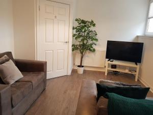 a living room with a couch and a flat screen tv at Carvetii - Edward House C - 2 Dbl bed 2nd floor flat in Dunfermline