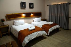 a hotel room with two beds and two lamps at Cest Si Bon Hotel in Otjiwarongo