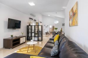 a living room with a black leather couch and a tv at House Casetta Filip in Krnica