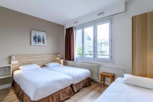 una camera d'albergo con due letti e una finestra di Comfort Hotel Rouen Alba a Rouen