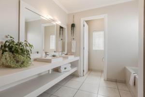 a bathroom with two sinks and a mirror at The Robberg Beach Lodge - Lion Roars Hotels & Lodges in Plettenberg Bay