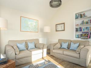 a living room with two couches and a book shelf at The Old Lifeboat House in Penmon