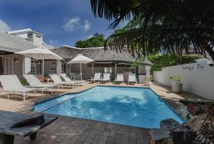 a swimming pool with chairs and a house at The Robberg Beach Lodge - Lion Roars Hotels & Lodges in Plettenberg Bay