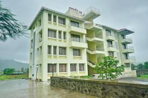 a large yellow building with balconies on it at Hotel Shiva's Inn in Trimbak