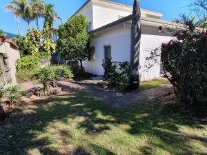 a white house with a palm tree in the yard at Number 1 Beach House in Rainbow Beach