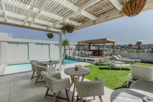 a patio with tables and chairs and a swimming pool at The Robberg Beach Lodge - Lion Roars Hotels & Lodges in Plettenberg Bay
