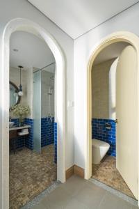 a bathroom with blue tiles and a tub and a toilet at Sofiana My Khe Hotel & Spa- Rooftop Pool Bar in Danang