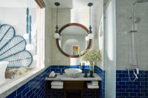 a blue tiled bathroom with a sink and a mirror at Sofiana My Khe Hotel & Spa- Rooftop Pool Bar in Danang