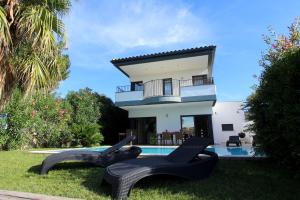 エンプリアブラバにあるLEON INMO Villa Olivia - 10039のスイミングプールと黒い椅子2脚が備わるヴィラです。