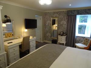 a bedroom with a bed and a desk and a television at The Belmore in Sale